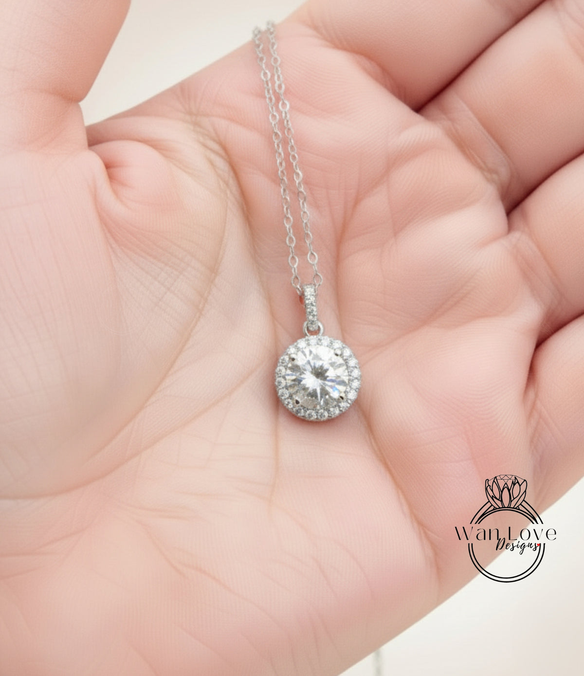 A hand holding a delicate necklace with a large, sparkling diamond pendant.