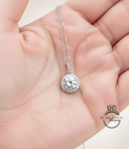A hand holding a delicate necklace with a large, sparkling diamond pendant.