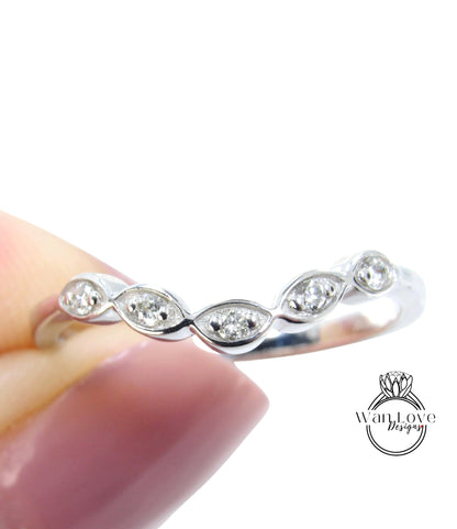 A close-up image of a person's hand holding a silver ring with a row of small diamonds on the band.
