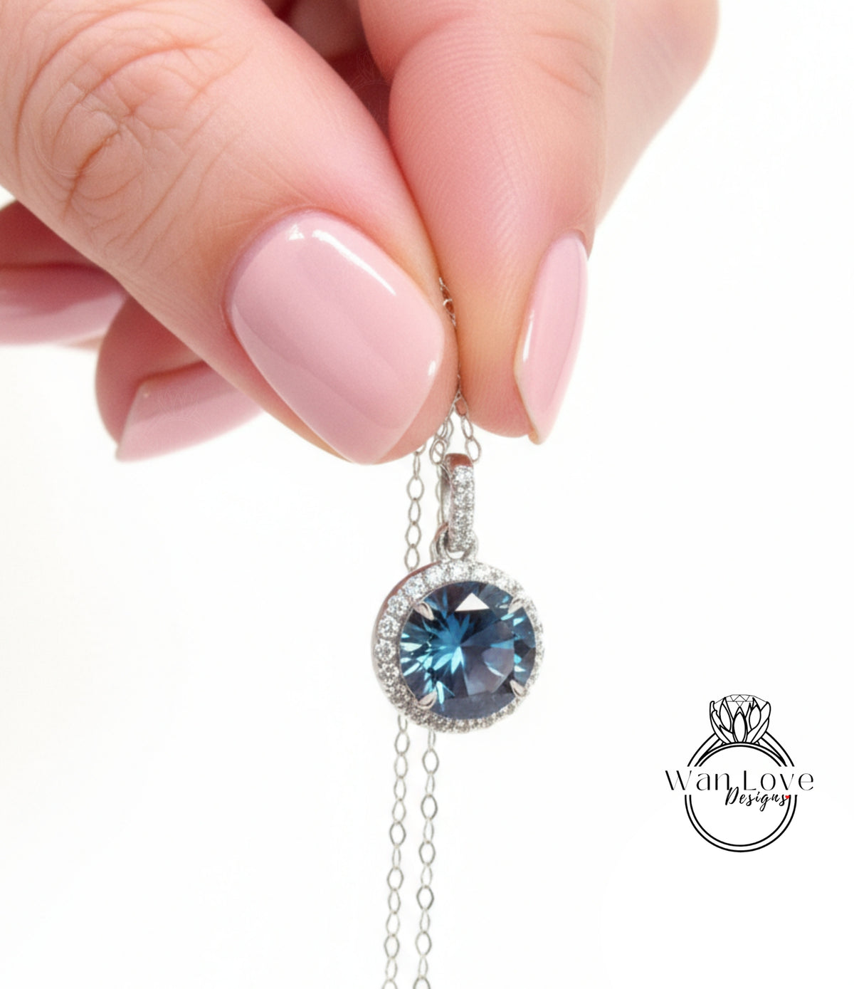A hand holding a necklace with a blue gemstone pendant.