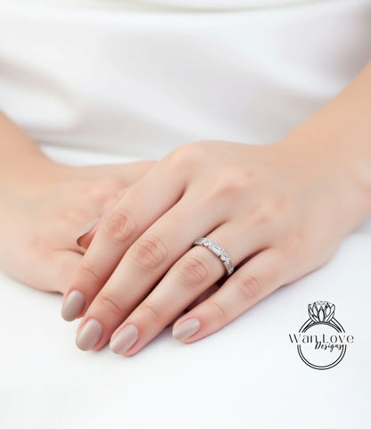 A close-up of a person's hand wearing a diamond ring, resting on a white surface.