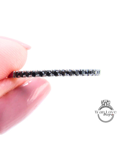 A hand holding a ring with a row of black diamonds along the band.