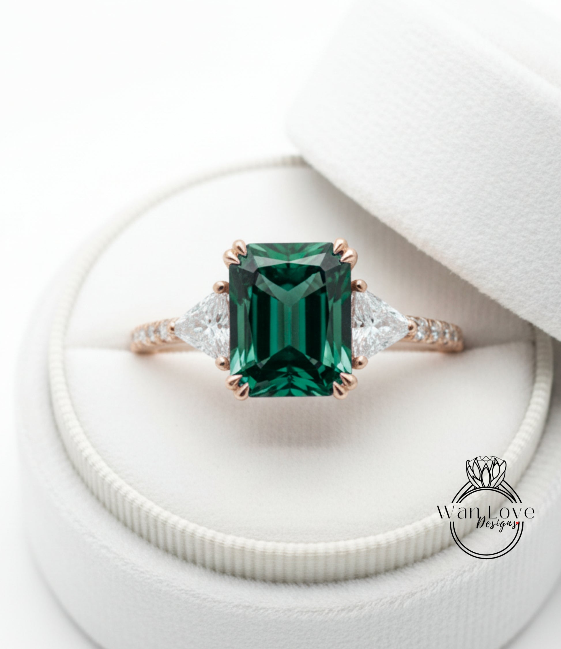 A beautiful engagement ring with a large, green gemstone set in a gold band, placed in a white jewelry box.