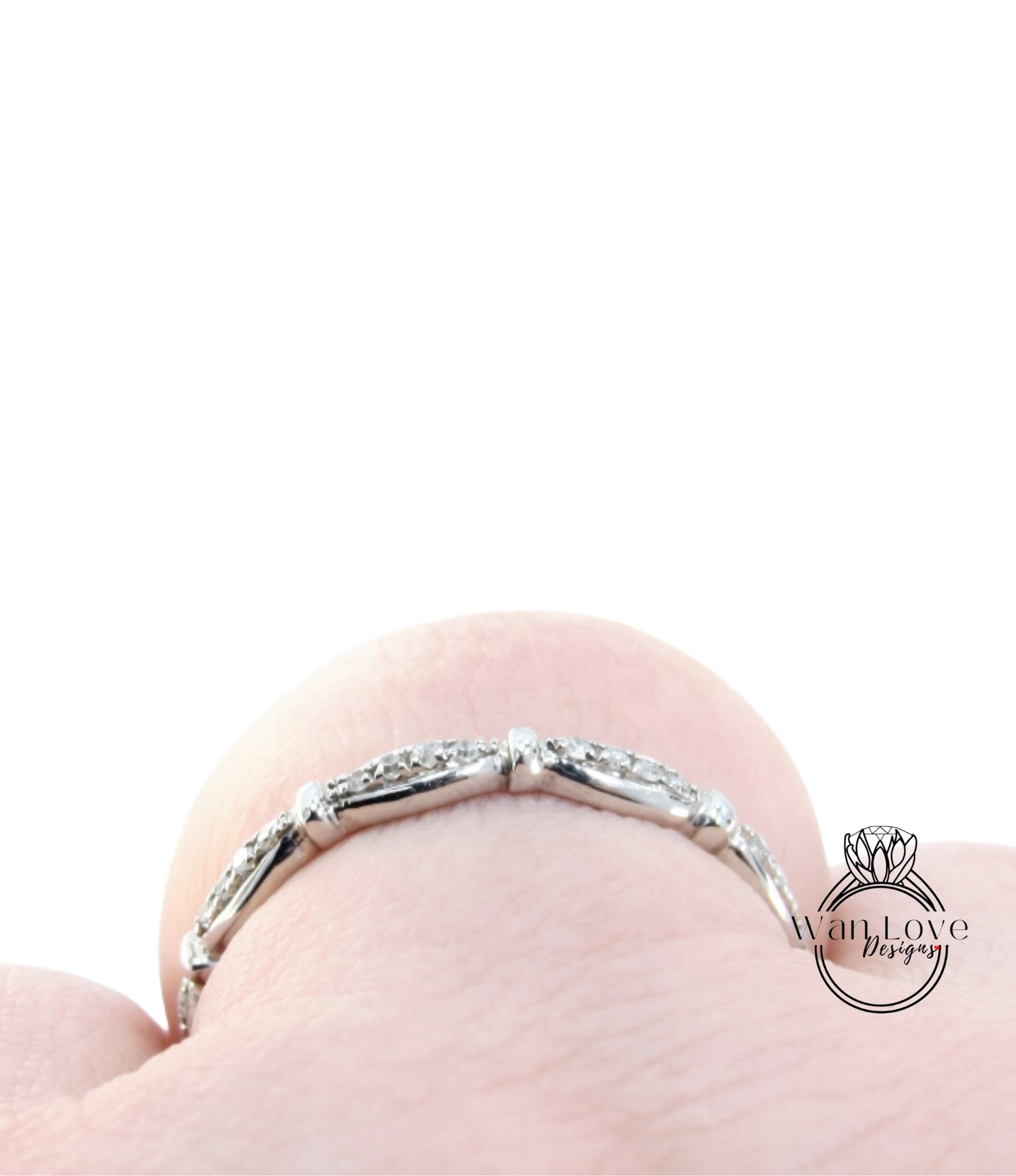 A close-up view of a silver ring with a row of small diamonds on the band, set against a plain white background.