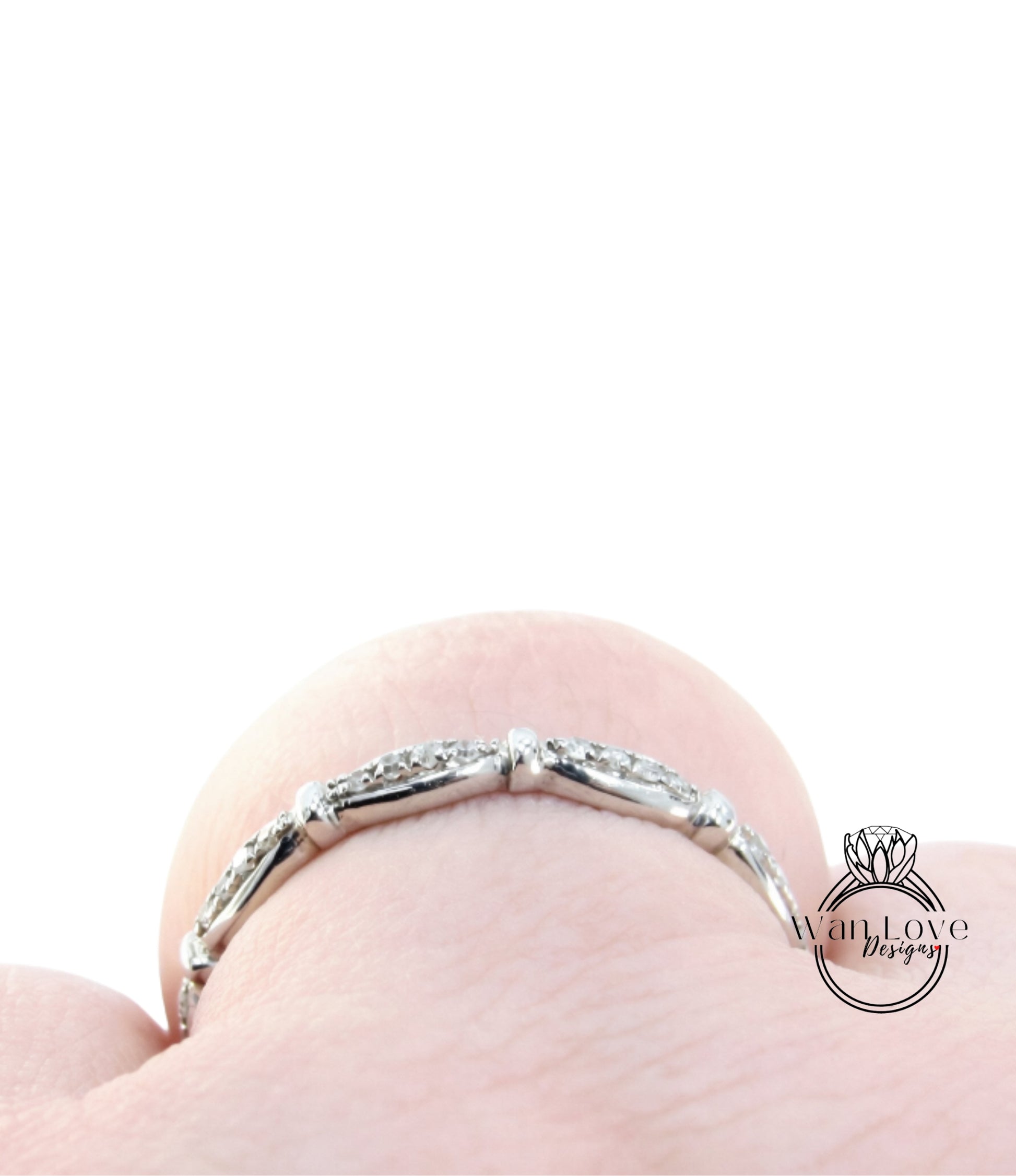 A close-up view of a silver ring with a row of small diamonds on the band, set against a plain white background.