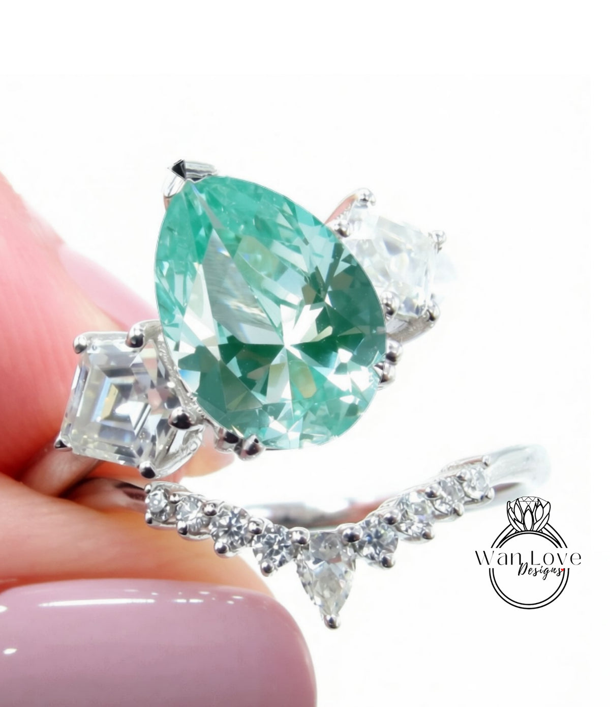 A close-up of a person's hand holding a ring with a large, green gemstone surrounded by smaller diamonds.