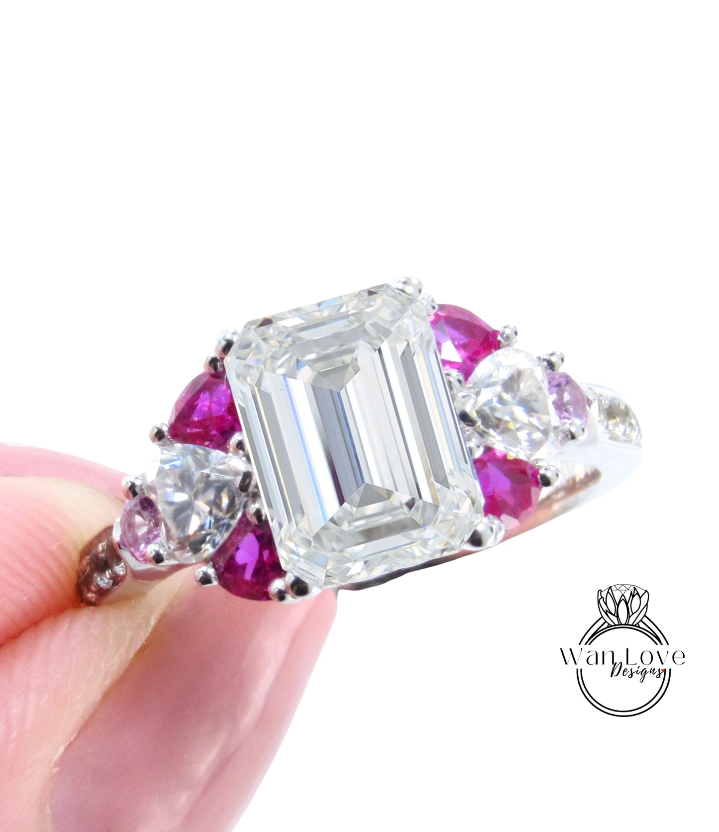 A close-up image of a person's hand holding a diamond engagement ring with a large central diamond surrounded by smaller diamonds and gemstones in various colors, including pink and purple.