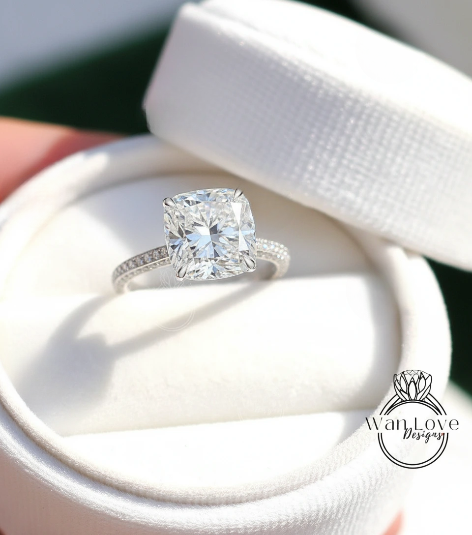 A large, clear diamond engagement ring is displayed in a white box, showcasing its intricate details and sparkling clarity.