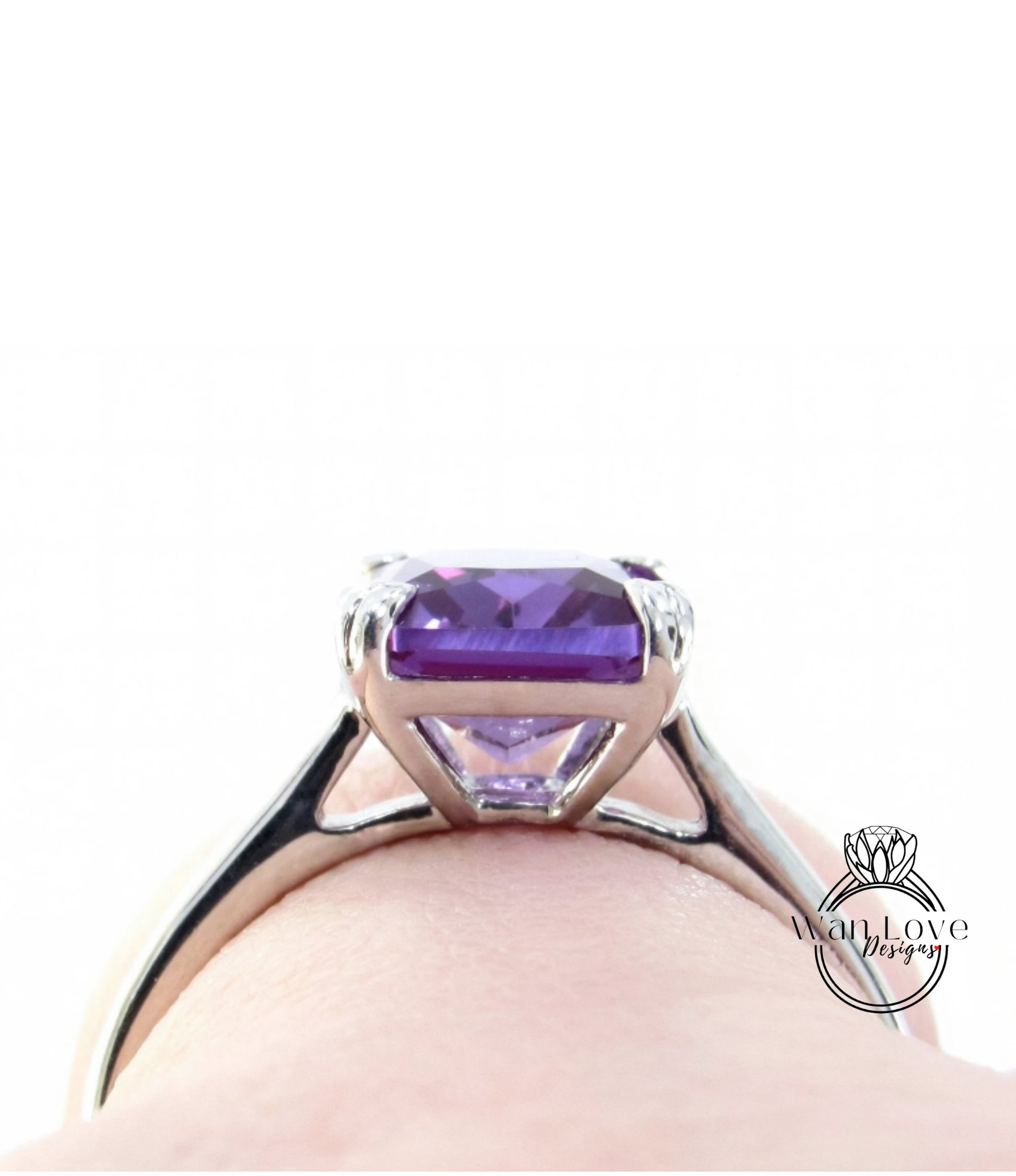A close-up view of a silver ring with a large, clear purple gemstone set in the center.