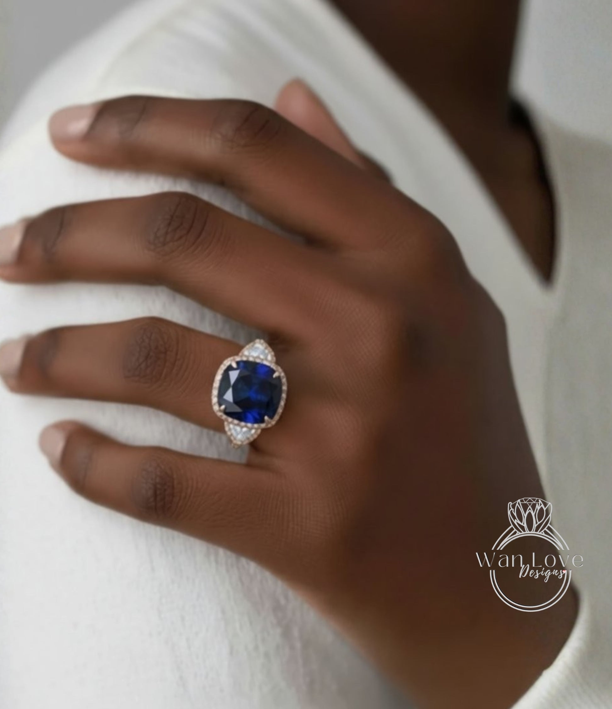 A close-up of a hand wearing a large, blue gemstone ring with a gold band.
