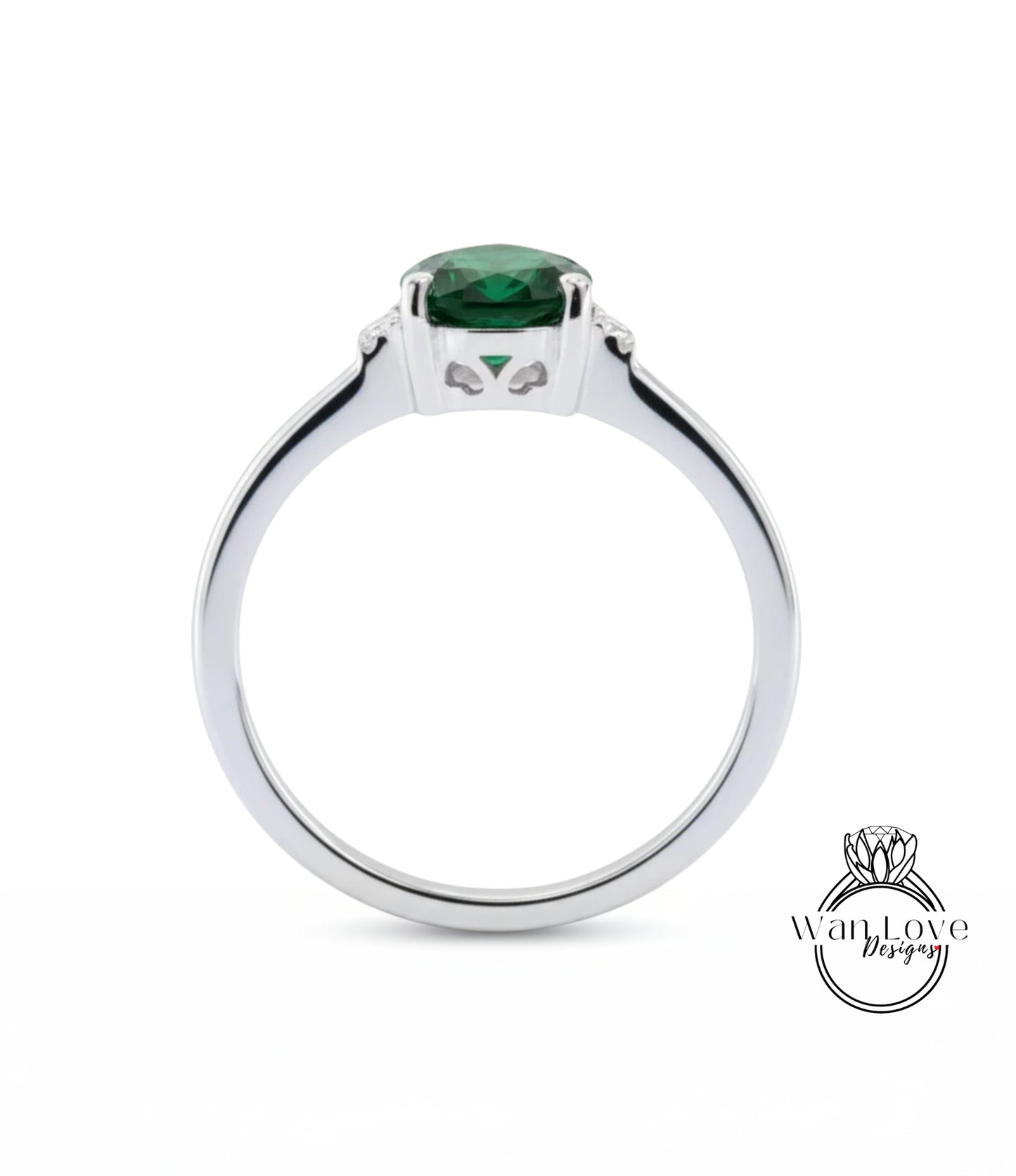 A silver ring with a large green gemstone, likely a diamond, set in the center.