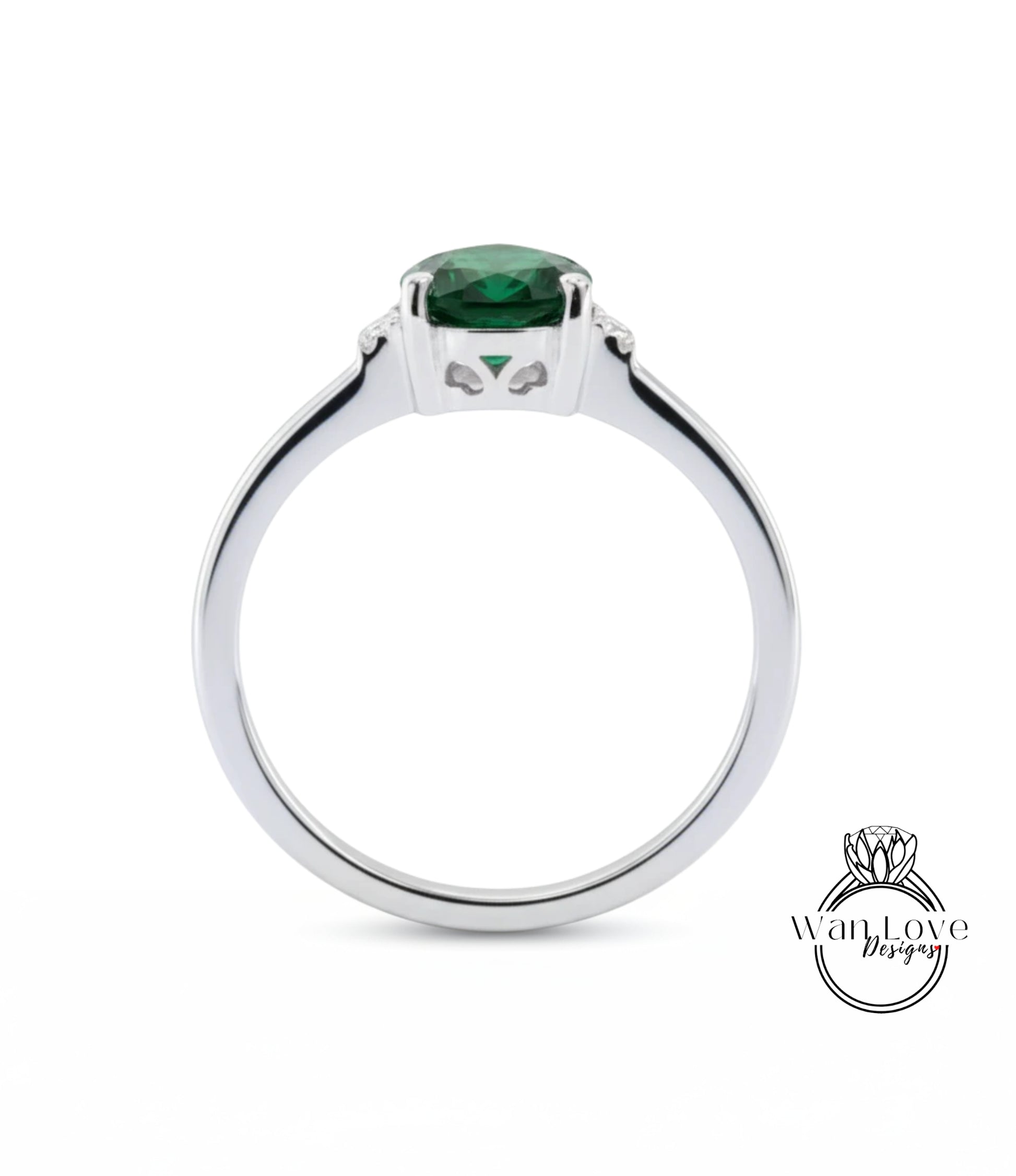 A silver ring with a large green gemstone, likely a diamond, set in the center.