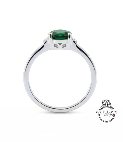 A silver ring with a large green gemstone, likely a diamond, set in the center.