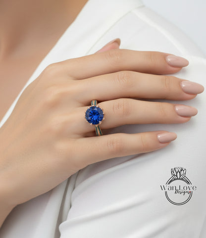 A close-up of a person's hand wearing a large blue gemstone ring on the ring finger.