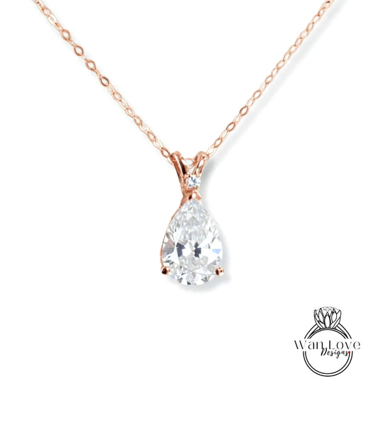 A close-up view of a delicate rose gold necklace with a large, clear pear-shaped diamond pendant.