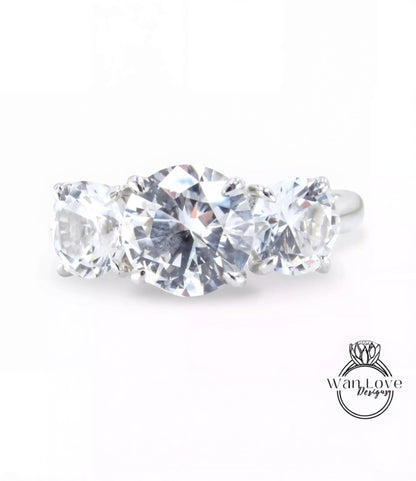 A close-up image of a diamond ring with three large, clear diamonds set in a silver band.