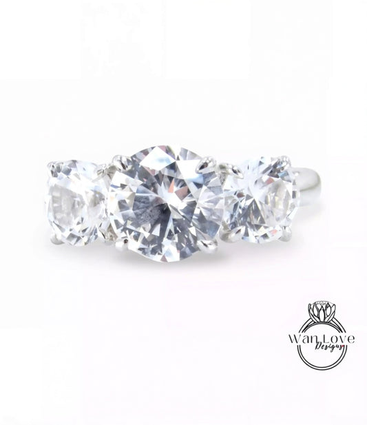 A close-up image of a diamond ring with three large, clear diamonds set in a silver band.