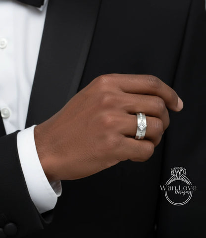 A close-up of a person's hand wearing a silver ring on the ring finger, with a black suit jacket visible in the background.