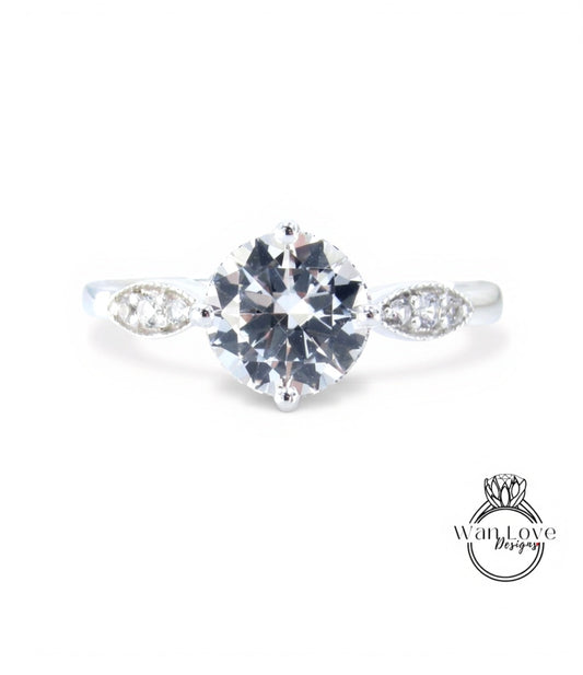 A close-up view of a diamond engagement ring with a large central diamond surrounded by smaller diamonds on either side.