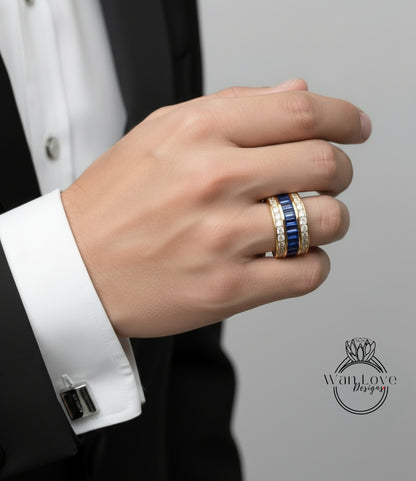 A close-up of a person's hand wearing a gold ring with blue gemstones, wearing a black suit jacket, and a white shirt cuff.