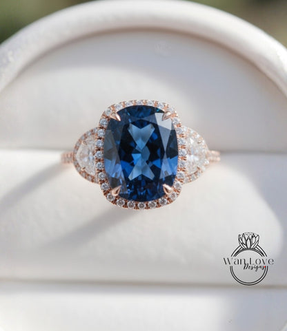 A close-up image of a large blue gemstone ring with a halo of smaller diamonds around the center stone.