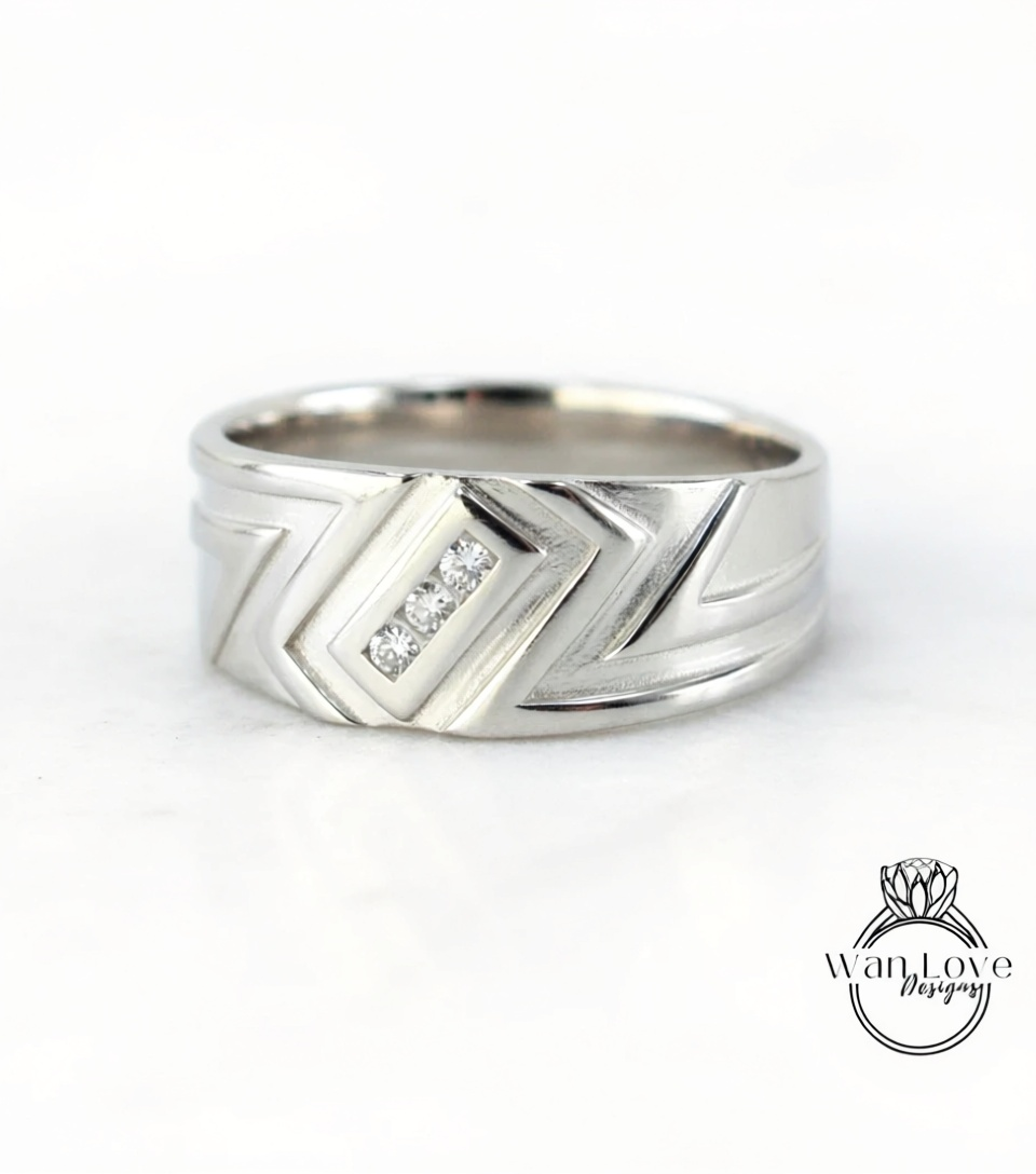 A silver ring with a geometric design and three small diamonds set in the center.