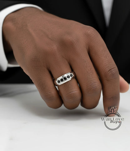A close-up of a person's hand wearing a silver ring with black stones.