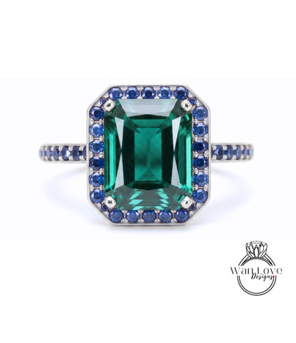 A large, rectangular green gemstone ring with a halo of smaller blue gemstones around the edges.