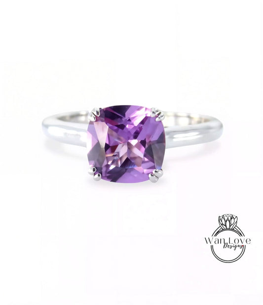 A silver ring with a large, square-cut amethyst gemstone set in the center.