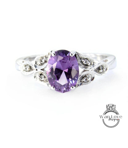 A silver ring with a large oval-shaped purple gemstone, surrounded by small diamonds or crystals.