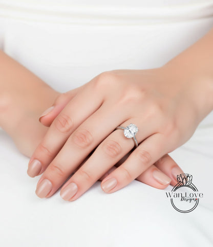 A close-up of a person's hand wearing a diamond engagement ring.