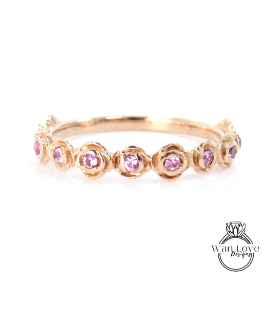 A gold ring with a row of pink gemstones, likely rubies, set in a decorative pattern.