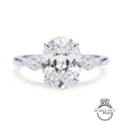 A close-up of a diamond engagement ring with a large oval-shaped diamond set in the center, surrounded by smaller diamonds on either side.