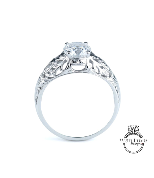 A close-up view of a silver engagement ring with a large central diamond and intricate floral designs around the band.