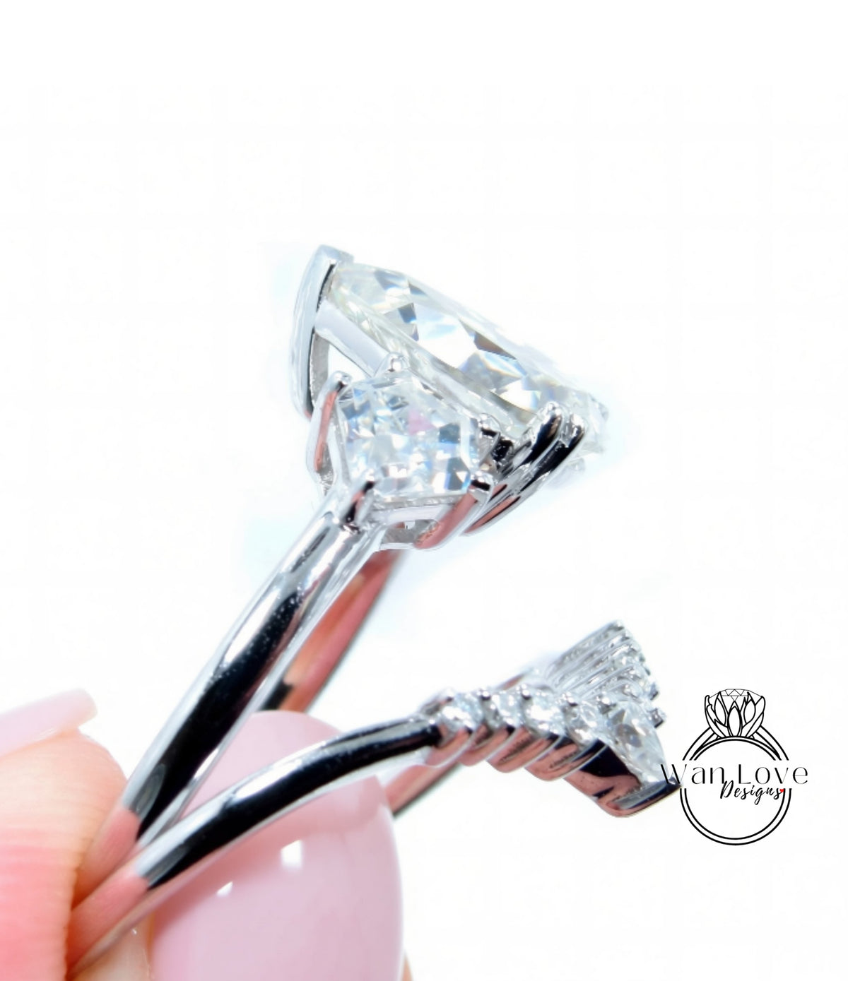 A close-up view of a diamond engagement ring with a large central diamond surrounded by smaller diamonds, held in a hand against a white background.