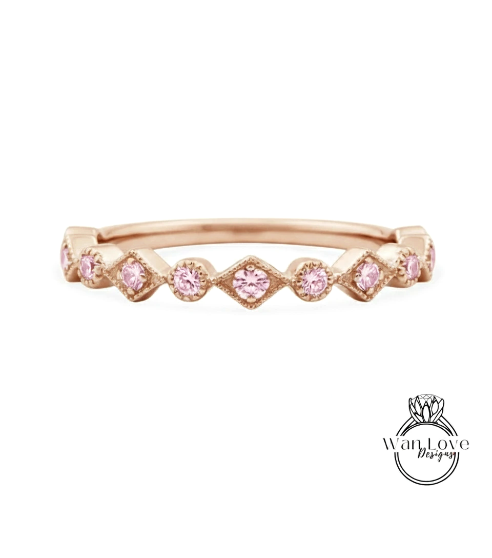 A rose gold ring with a row of pink diamonds set in a diamond pattern.