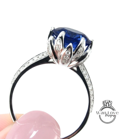 A close-up image of a silver ring with a large blue gemstone, possibly a sapphire, set in a decorative metal design.