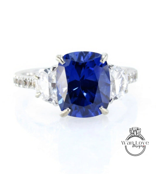 A stunning blue gemstone engagement ring with a large central blue gemstone surrounded by smaller diamonds on either side.