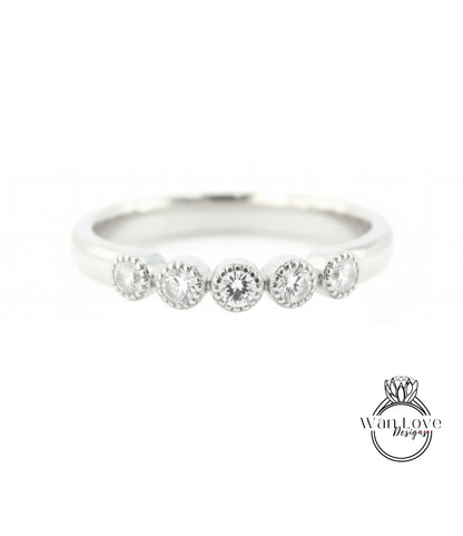 A silver ring with a row of five round diamonds set in the band.