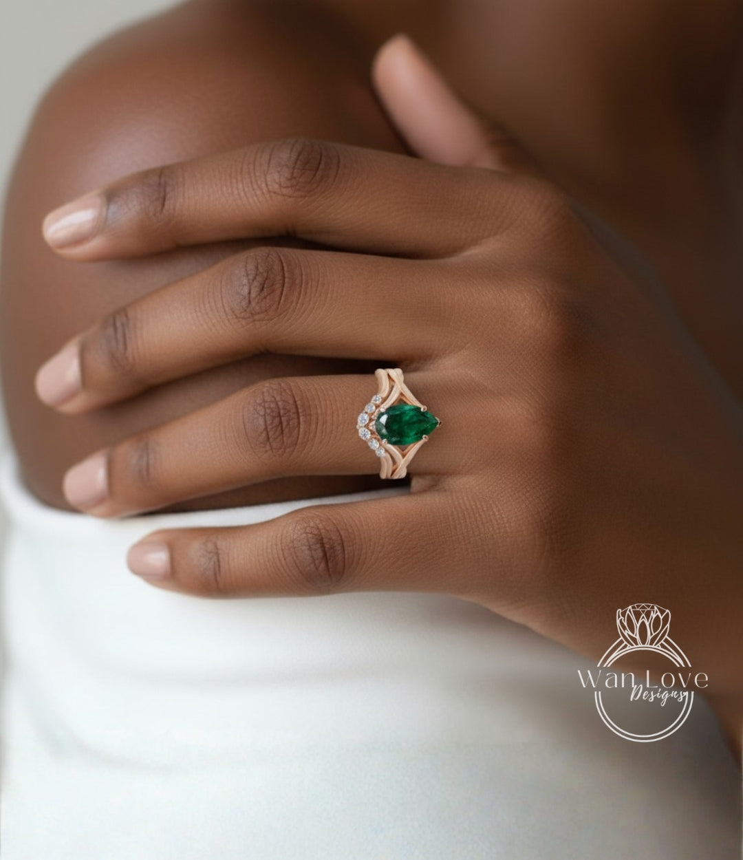 A close-up of a person's hand wearing a gold ring with a large green gemstone, resting on a white surface.