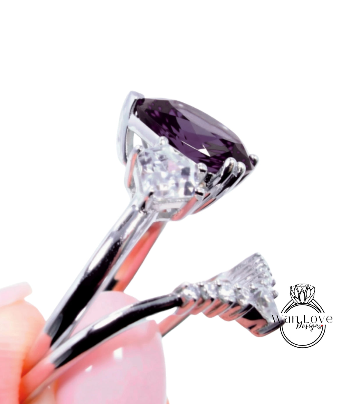 A close-up view of a silver ring with a large purple gemstone, held in a hand against a white background.