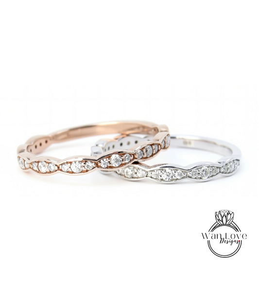 A close-up image of two rings with a row of diamonds set in the center, one in a rose gold color and the other in silver.