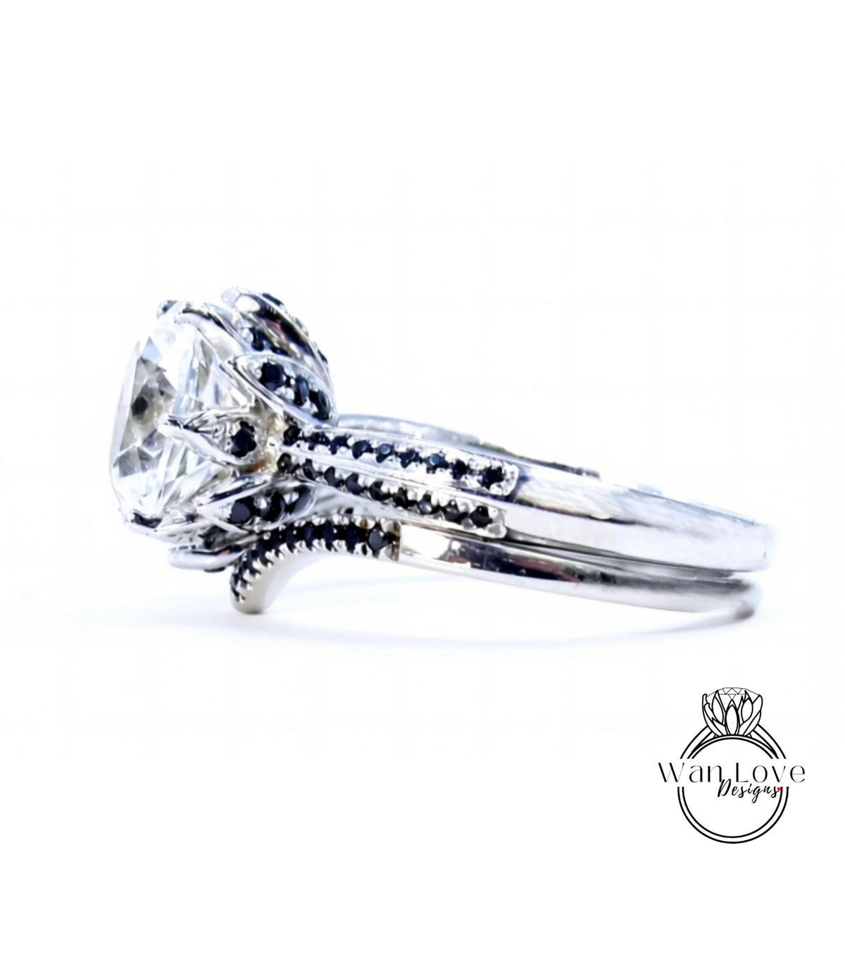 A close-up view of a silver ring with a large, clear gemstone, possibly a diamond, set in a decorative band with small black stones.