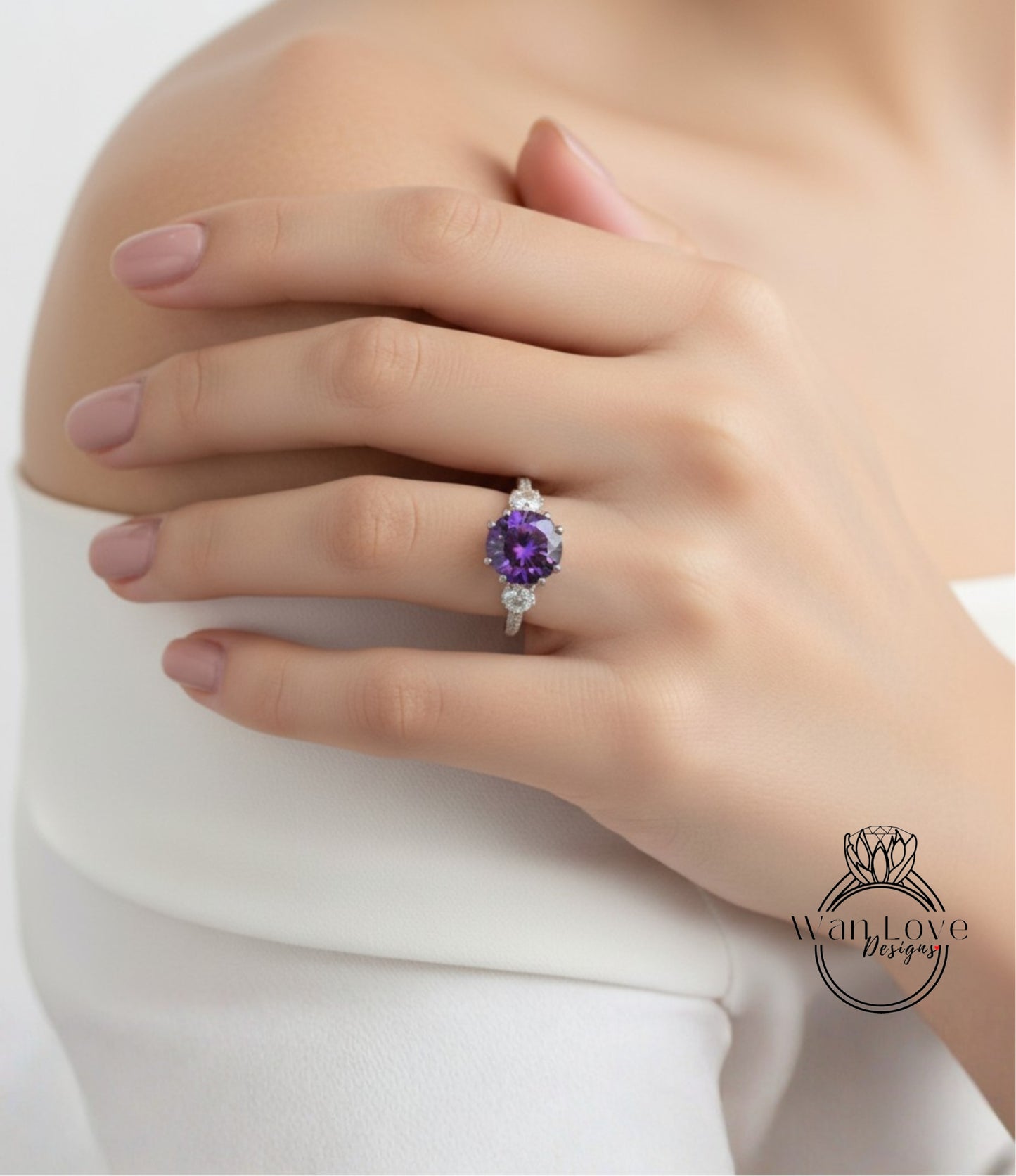 A close-up of a hand wearing a ring with a large purple gemstone, resting on a white sleeve.