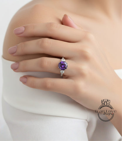 A close-up of a hand wearing a ring with a large purple gemstone, resting on a white sleeve.