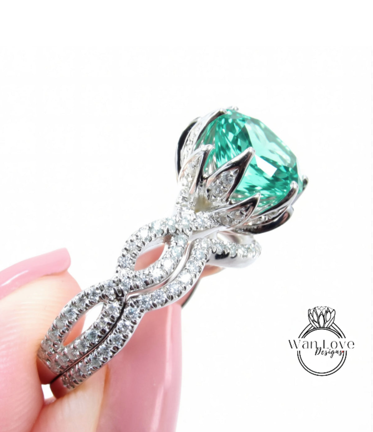A close-up of a person's hand holding a diamond ring with a large, green gemstone.