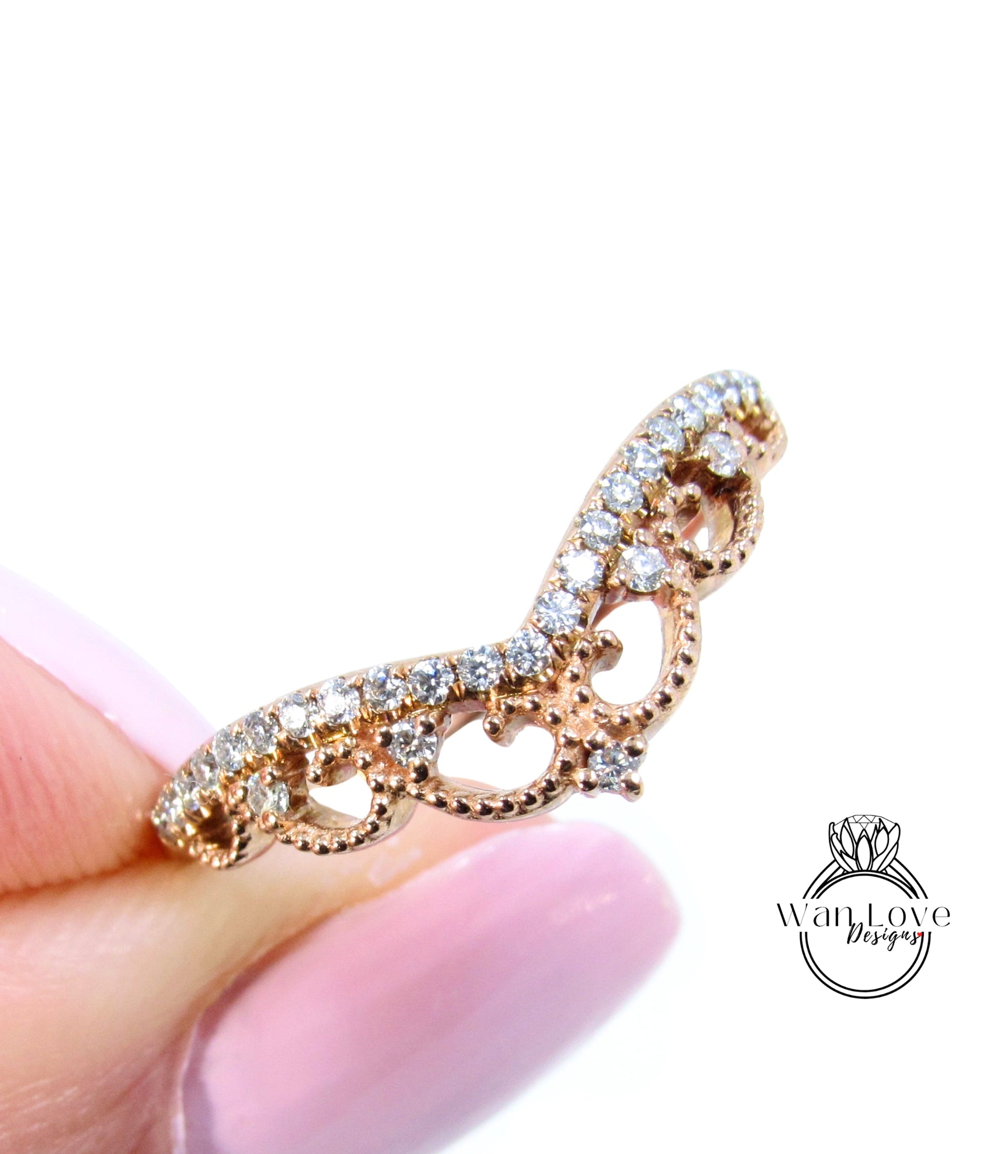 A close-up image of a person's hand holding a gold ring with a decorative design.