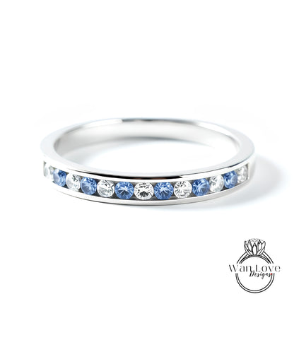 A silver ring with a row of blue and white diamonds set in it.
