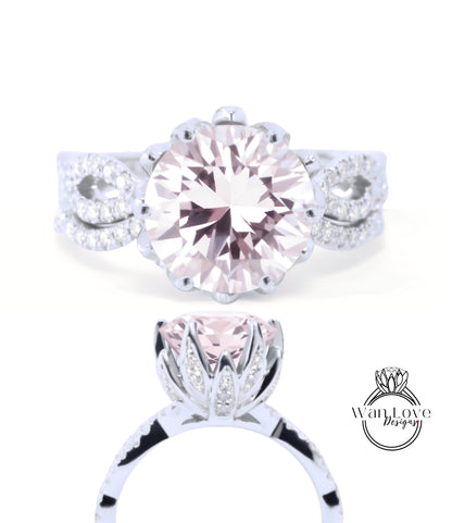 A close-up view of a beautiful pink diamond engagement ring with a large central diamond surrounded by smaller diamonds and a delicate floral design.