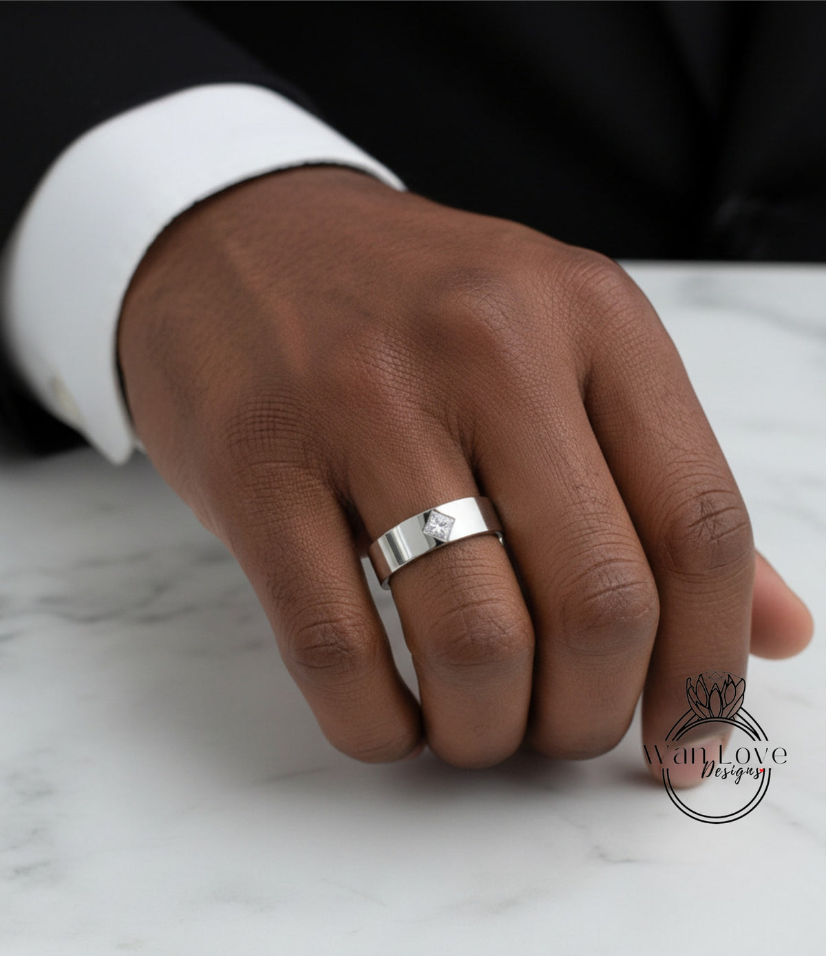 A close-up of a person's hand wearing a silver ring on the ring finger.